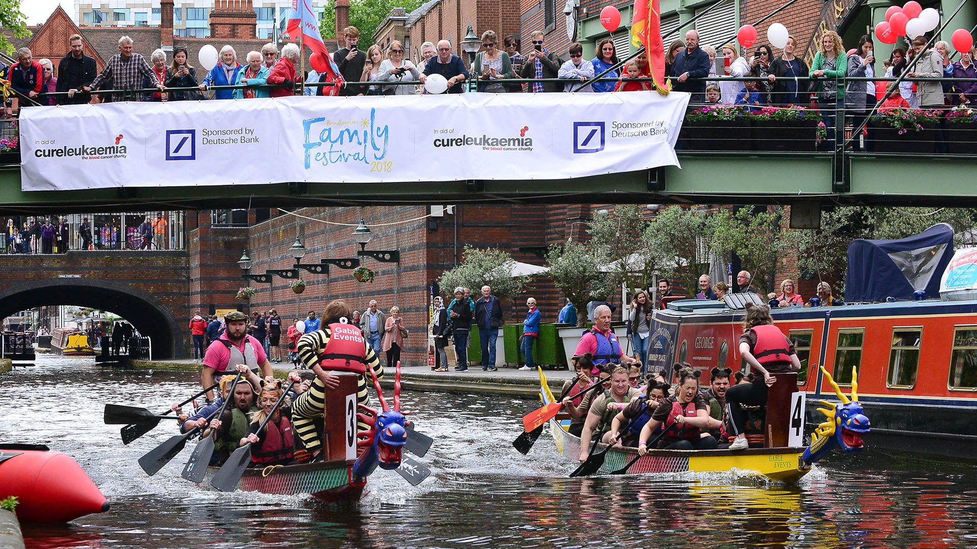 People in rowboats, rowing down a canal for a charity event in Brindleyplace, Birmingham.