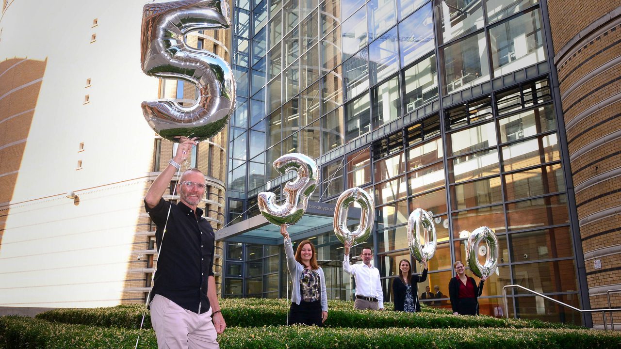 Group of people holding numbered balloons in Brindleyplace, Birmingham.