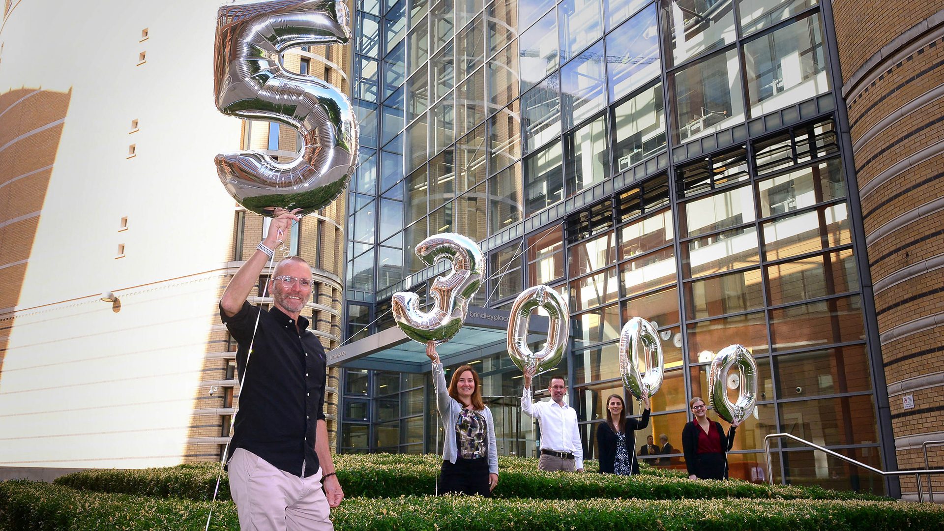 Group of people holding numbered balloons in Brindleyplace, Birmingham.