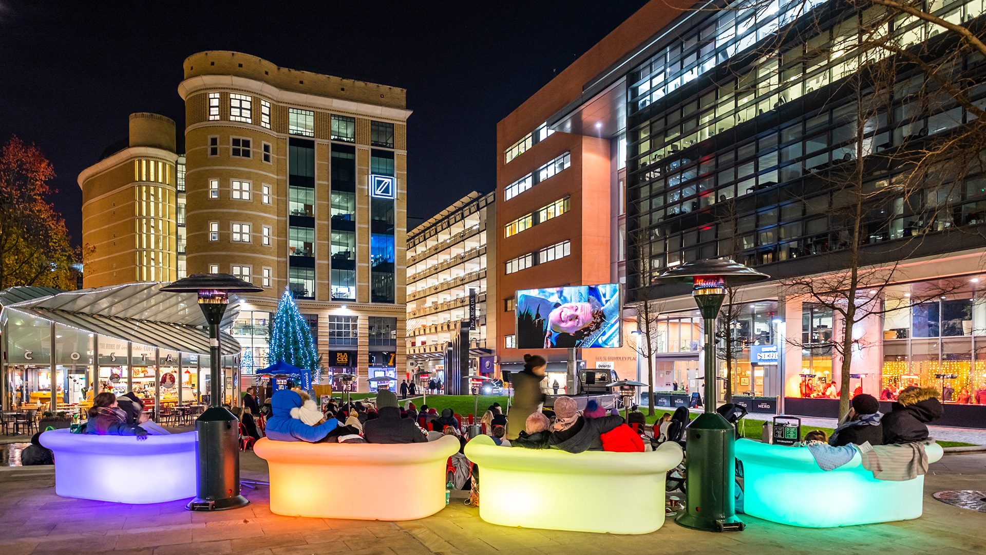Four sofas in front of an outdoor city center cinema screen