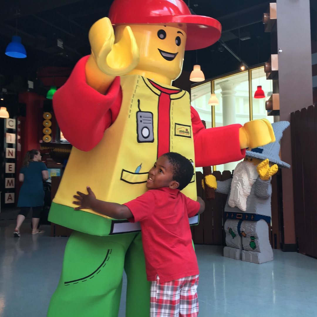 Child hugging a large lego statue at the LEGOLAND discover centre in Birmingham.