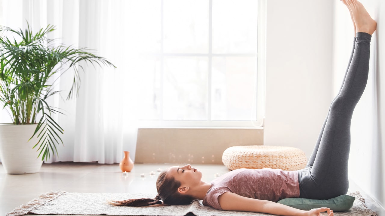 Woman lying on floor with legs stretched upwards doing yoga.