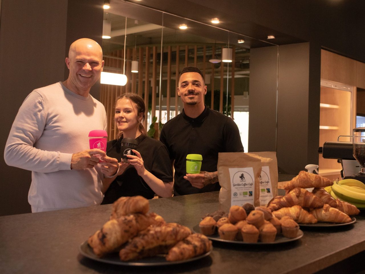 A picture of Gorilla Cafe employees behind a counter with various pastries on plates in front of them.