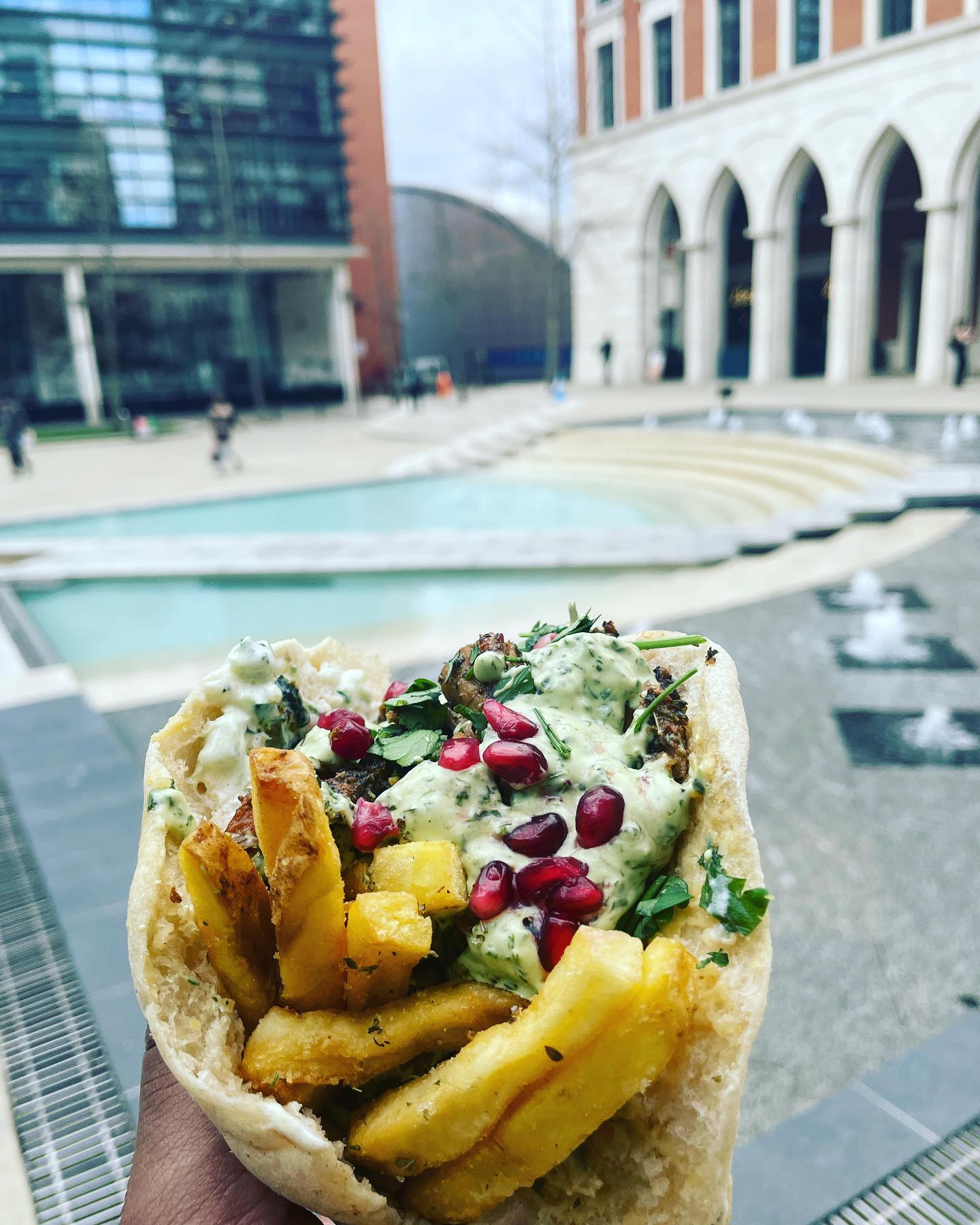 A Gyros being held up with Cental Square in the background.