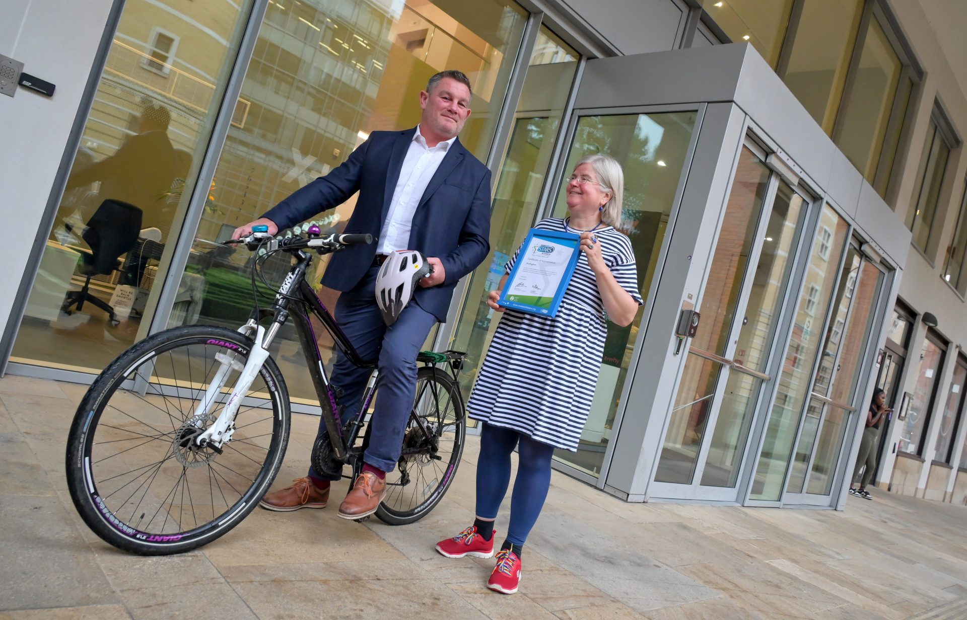 Matt Long, senior asset manager for Praxis at Brindleyplace stands with a bike while Councillor Liz Clements, cabinet member for Transport at Birmingham City Council holds the Green/Approved Modeshift STARS Travel Plan accreditation while in front of Foundry 6 Brindleyplace.